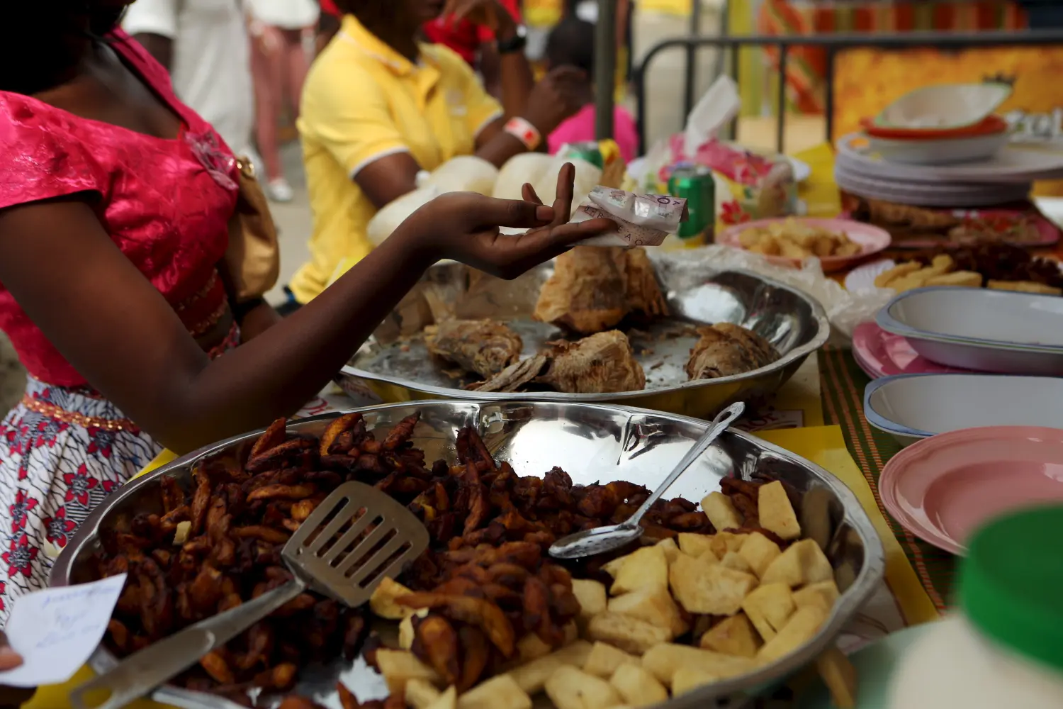 A woman hands over a 10,000 CFA ($16.50) note to pay for food during the attieke and fish festival in Abidjan, Ivory Coast, January 30, 2016.  REUTERS/Joe Penney - GF10000290428