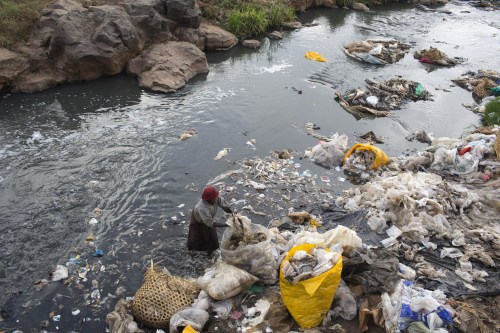 A woman recycles plastic bags from a river near the Dondora dumpsite close to the slum of Korogocho in the capital Nairobi, Kenya, March 17, 2015.