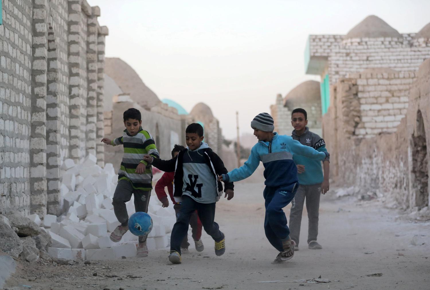 Children play football at the graveyards (City of the Dead) called locally "Zawiyyet al-Mayyiteen" in Minya Governorate, Upper Egypt January 8, 2019. REUTERS/Mohamed Abd El Ghany - RC1217CE1350