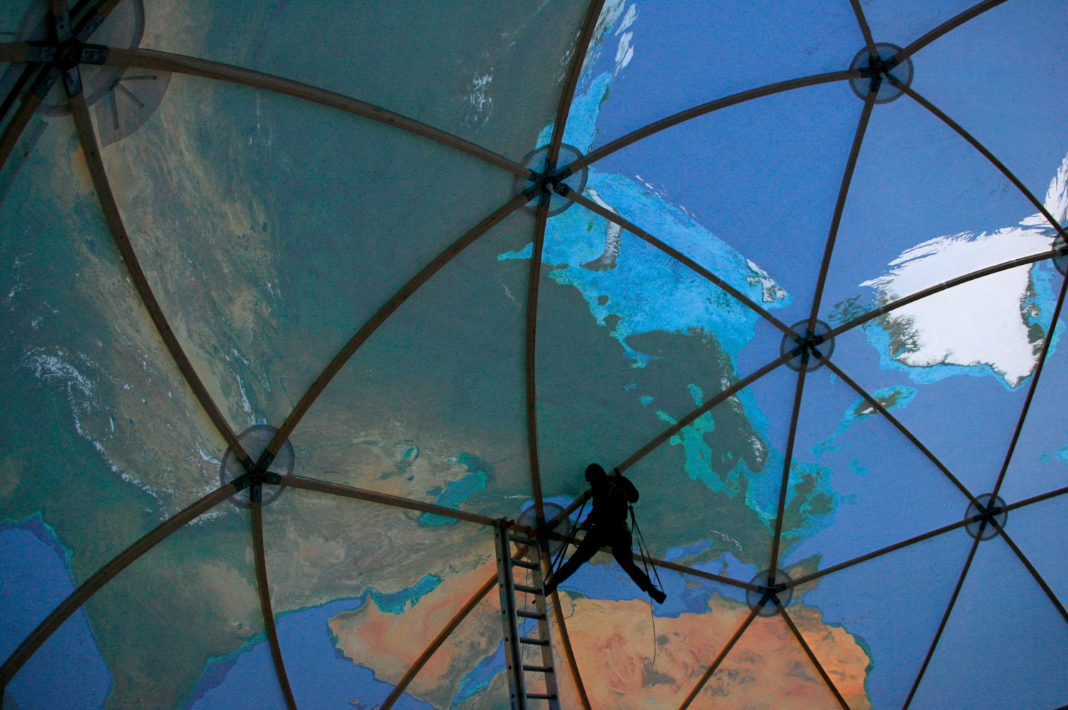 A Greenpeace activist makes adjustments while hanging from the ceiling inside a giant model of the globe near Konin open mine, 70 km from Poznan, western Poland December 3, 2008. Greenpeace established a camp to protest against the damage it says the Konin mine is doing to the climate, regional tourism and farming, and against the planned opening of new sites. REUTERS/Kacper Pempel    (POLAND) - GM1E4C406SK01