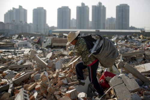 Migrant worker Wang Jun carries scrap material she collected from debris of demolished buildings at the outskirts of Beijing, China October 1, 2017. Picture taken October 1, 2017. REUTERS/Thomas Peter - RC1FA1BF06B0