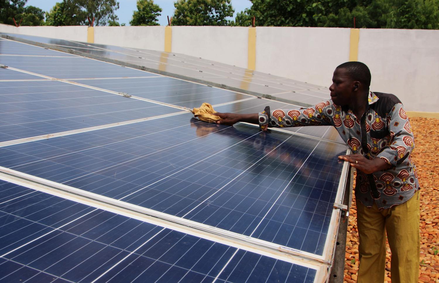 A technician cleans solar panels, part of the BBOXX and EDF solar energy system used to provide electricity to Sikpe Afidegnon village, Togo May 16, 2019. Picture taken May 16, 2019. REUTERS/Noel Kokou Tadegnon - RC123FE24560