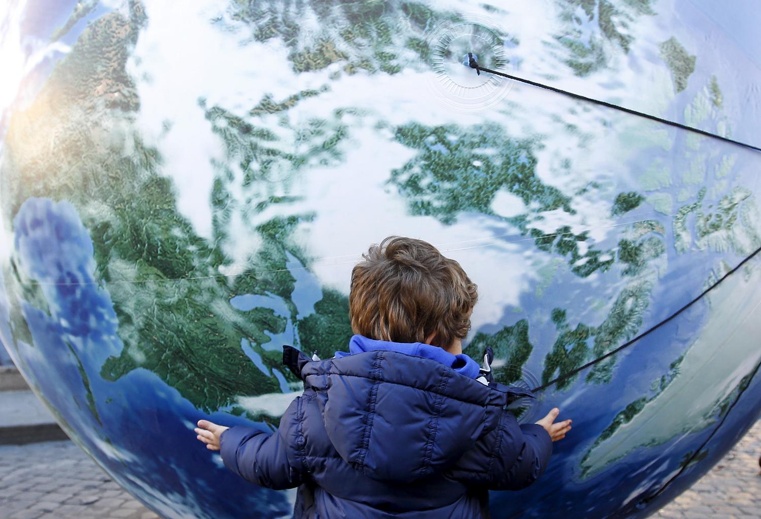 A child embraces a globe shaped balloon during a rally held ahead of the start of the 2015 Paris World Climate Change Conference, known as the COP21 summit, in Rome, Italy , November 29, 2015. REUTERS/Alessandro Bianchi - GF20000078554