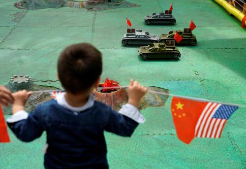 A boy looks at remote control tank toys next to the flags of China and the U.S. at a park in Shanghai, China, May 29, 2019. REUTERS/Aly Song - RC1502D3D7F0