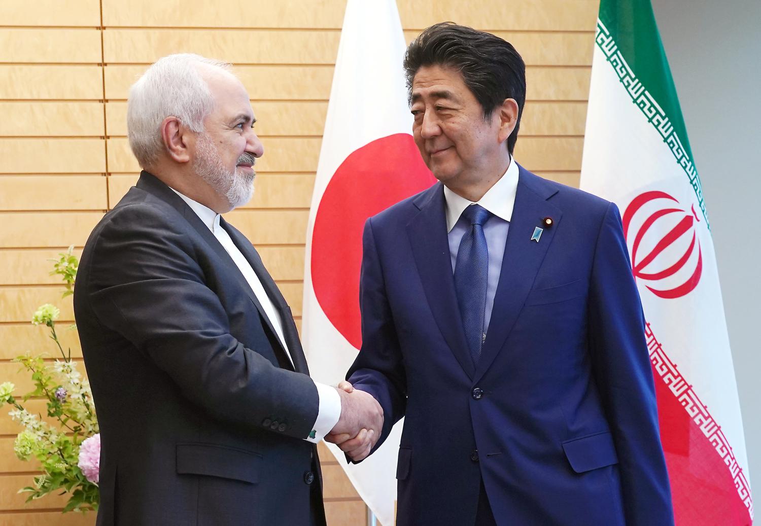 Iranian Foreign Minister Mohammad Javad Zarif, left, and Japanese Prime Minister Shinzo Abe, right, shake hands at Abe's official residence in Tokyo Thursday, May 16, 2019. Eugene Hoshiko/Pool via REUTERS - RC19838C3890