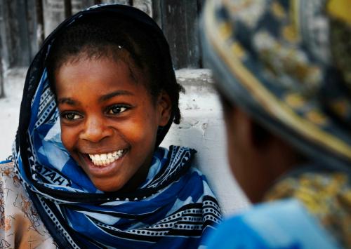 A girl smiles while playing a game with a friend in the village of Bwejuu on Zanzibar island, Tanzania, December 2, 2007. Picture taken December 2, 2007. REUTERS/Finbarr O'Reilly (TANZANIA) - GM1DWSSPAUAA