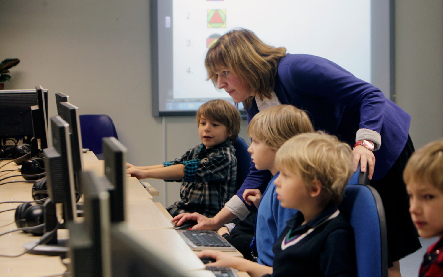 Teacher Kristi Rahn (C) helps to first grade students during a computer lesson in school in Tallinn September 25, 2012. Estonian Tiger Leap Foundation has launched a program called "ProgeTiiger" where Estonian students will be introduced to computer programming and creating web and mobile applications. According to representatives from the foundation, the program will start with students in the first grade, which starts around the age of 7, and will continue through a student's final years of public school, around age 15.  REUTERS/Ints Kalnins (ESTONIA - Tags: EDUCATION SCIENCE TECHNOLOGY) - GM1E89P1PG901
