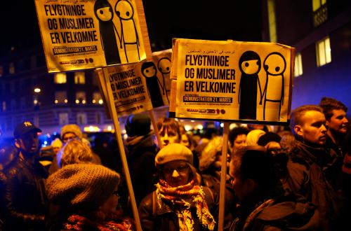 People hold banners reading "Refugees and Muslims are welcome" during a memorial service held for those killed on Saturday by a 22-year-old gunman, in Copenhagen February 16, 2015. Danish police said on Monday they had charged two people with aiding the man suspected of shooting dead two people in attacks on a synagogue and an event promoting free speech in Copenhagen at the weekend. The shootings, which Danish Prime Minister Helle Thorning-Schmidt called acts of terrorism, sent shockwaves through Denmark and have been compared to the January attacks in Paris by Islamist militants that killed 17. REUTERS/Leonhard Foeger (DENMARK  - Tags: CRIME LAW POLITICS RELIGION CIVIL UNREST)   - LR2EB2G1L133Y