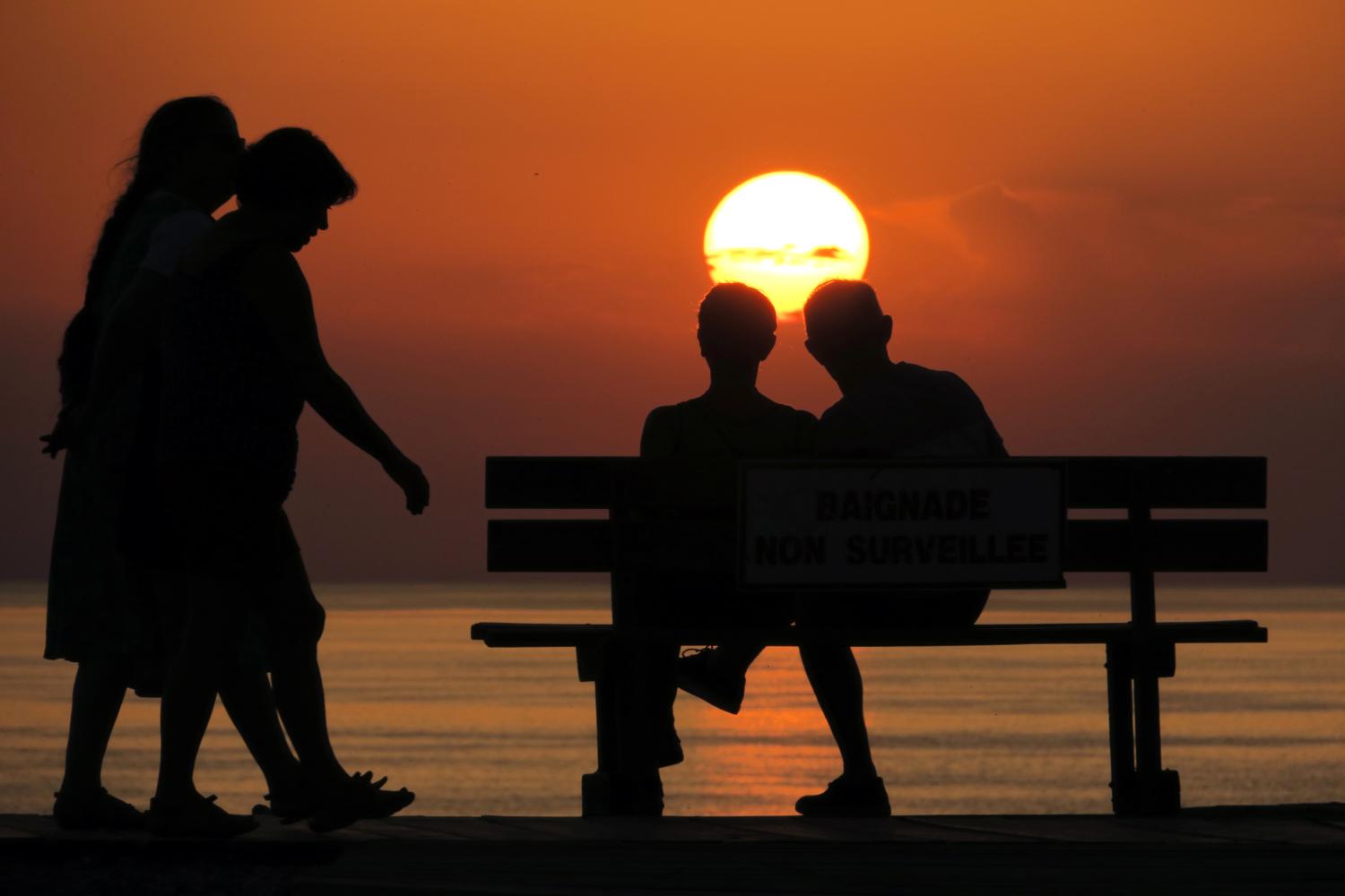 People walk along a pebbled beach during sunset as a heatwave hits France, in Cayeux-sur-Mer, France, June 29, 2019. REUTERS/Pascal Rossignol - RC12ECCBA720