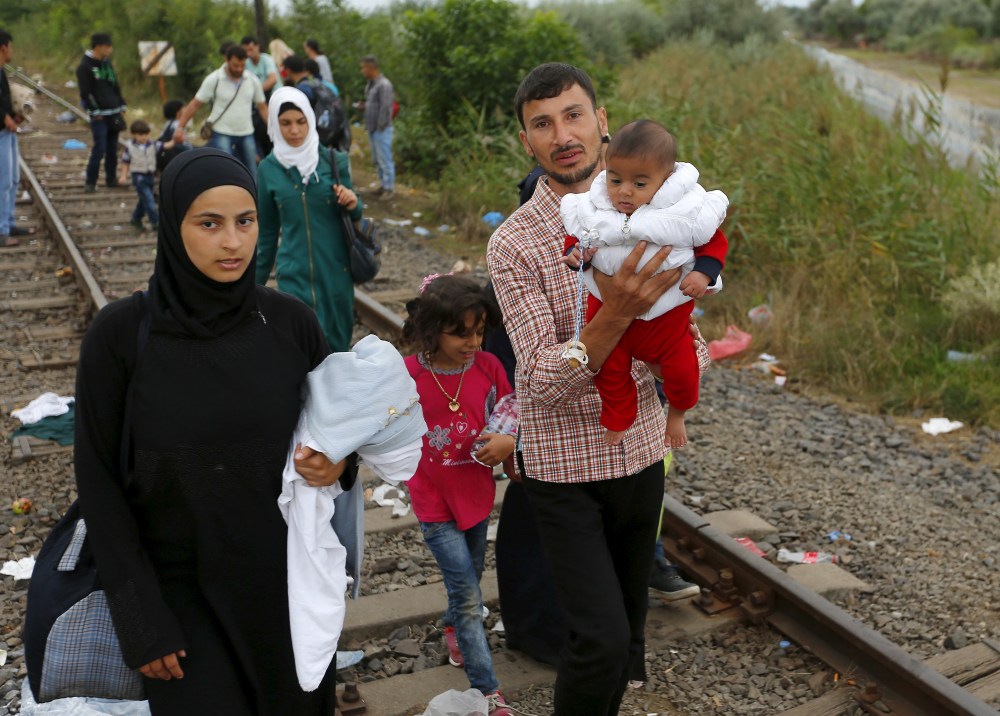 Syrian migrants walk along a railway track after crossing the Hungarian-Serbian border into Hungary, near Roszke, August 26, 2015. Hungary's government has started to construct a 175-km-long (110-mile-long) fence on its border with Serbia in order to halt a massive flow of migrants who enter the EU via Hungary and head to western Europe. REUTERS/Laszlo Balogh - GF10000182998