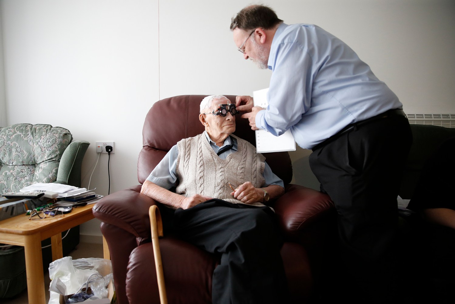 Resident Ernie Mayes, 89, has his eyes checked by Optometrist Ray Small in his flat at the Colbrooke House care facility run by a private company working on behalf of the local government and housing association in southeast London February 13, 2015. The provision of care for those who can no longer look after themselves but do not require a place in hospital is one of the biggest problems facing the state-funded National Health Service. The involvement of the private sector in critical services remains a contentious issue in Britain after large outsourcers failed in previous high profile contracts. REUTERS/Suzanne Plunkett (BRITAIN - Tags: POLITICS HEALTH SOCIETY) - LM1EB2J0R3L01