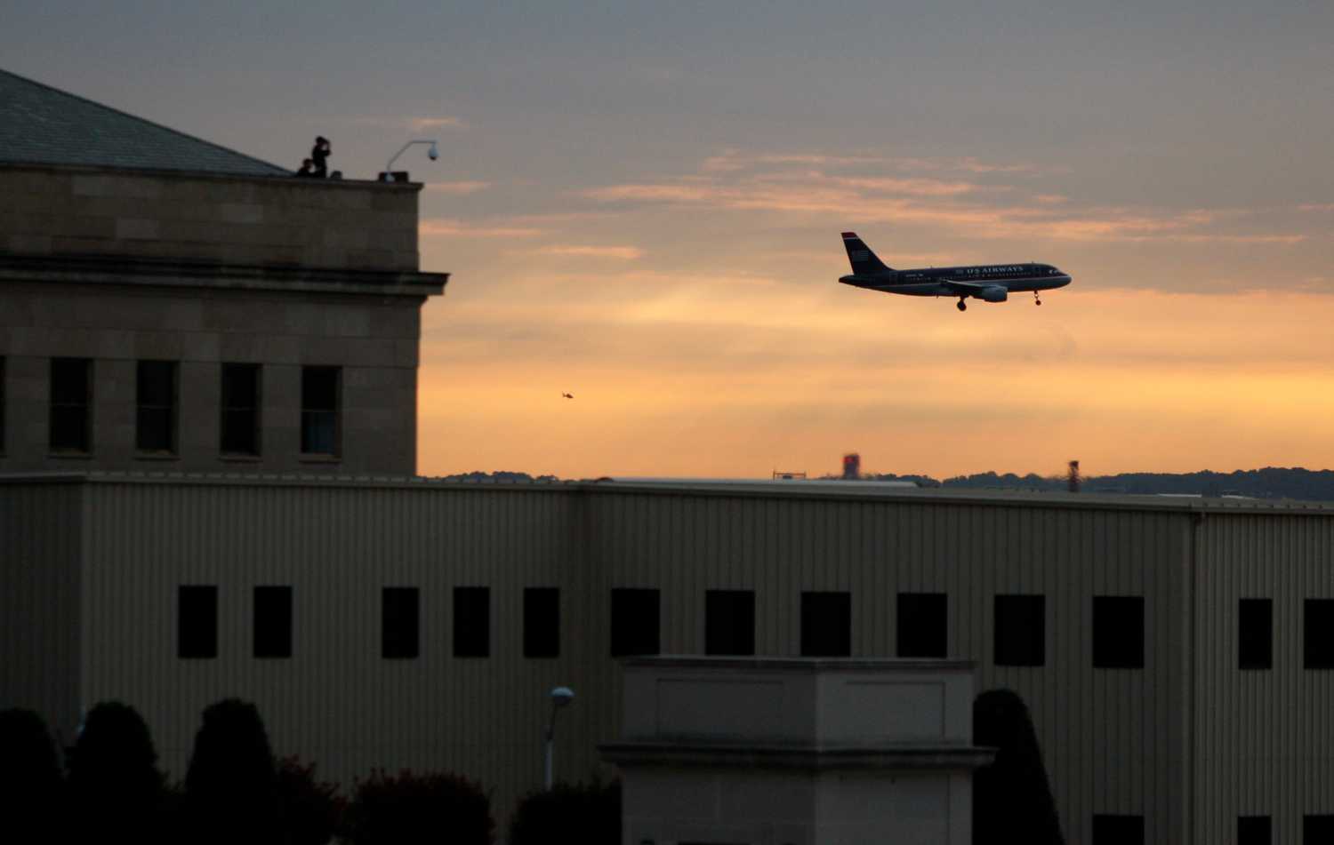 A commercial plane flies past the Pentagon as security watch from the roof September 11, 2008. A ceremony dedicating the first major permanent U.S. memorial to commemorate the September 11 attacks, where 184 victims died in the assault on the Pentagon, will be held Thursday.  REUTERS/Jason Reed   (UNITED STATES) - GM1E49B1M3S01