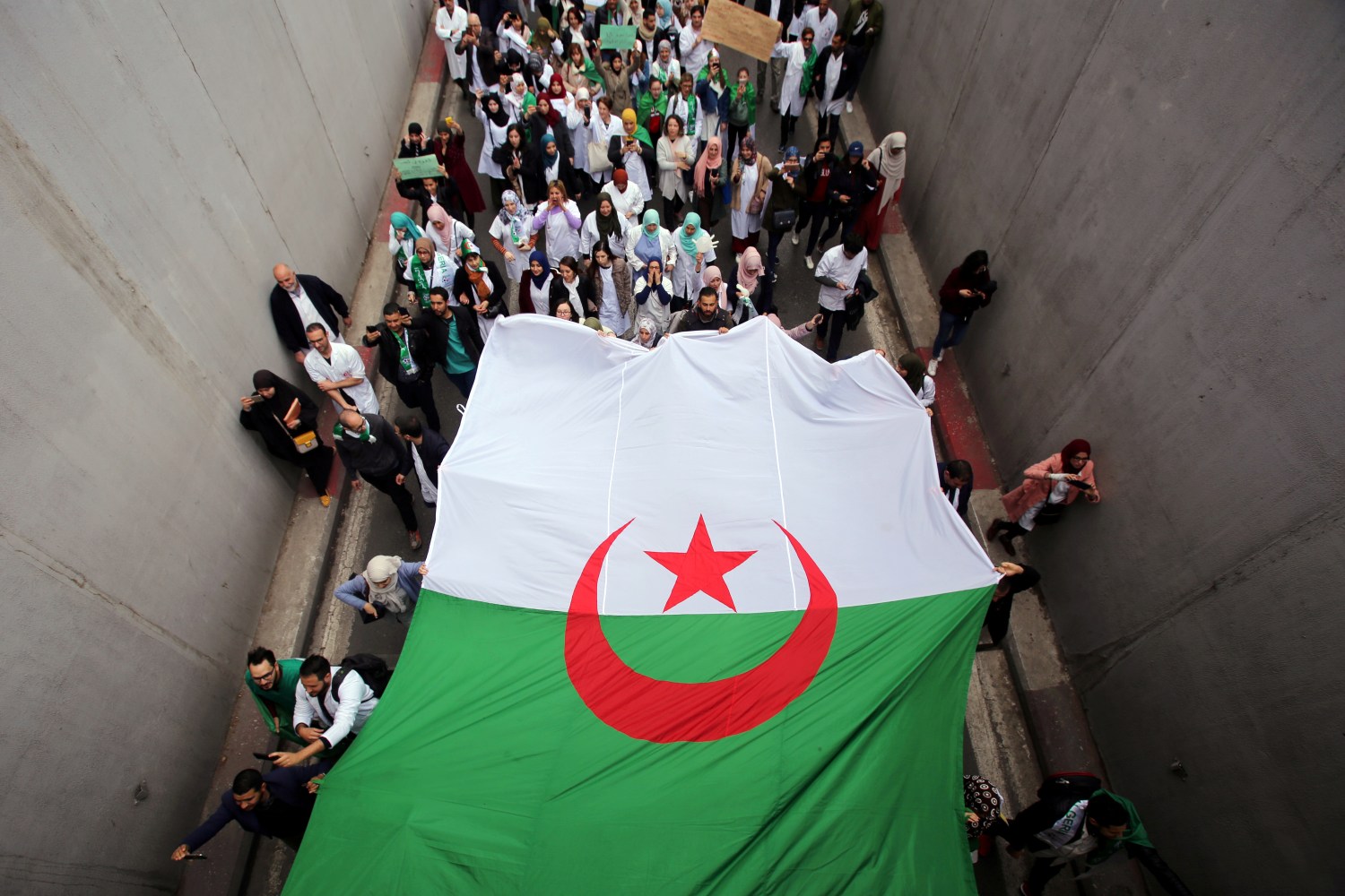 Health workers carry a national flag as they march during a protest calling on President Abdelaziz Bouteflika to quit, in Algiers, Algeria March 19, 2019. REUTERS/Ramzi Boudina TPX IMAGES OF THE DAY - RC16969E1C30
