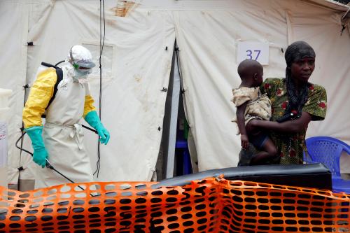 A health worker sprays disinfectant near a suspected Ebola patient holding a baby at an Ebola treatment centre in the Eastern Congolese town of Butembo in the Democratic Republic of Congo, March 27, 2019. Picture taken March 27, 2019. REUTERS/Baz Ratner - RC1D9E7A2400