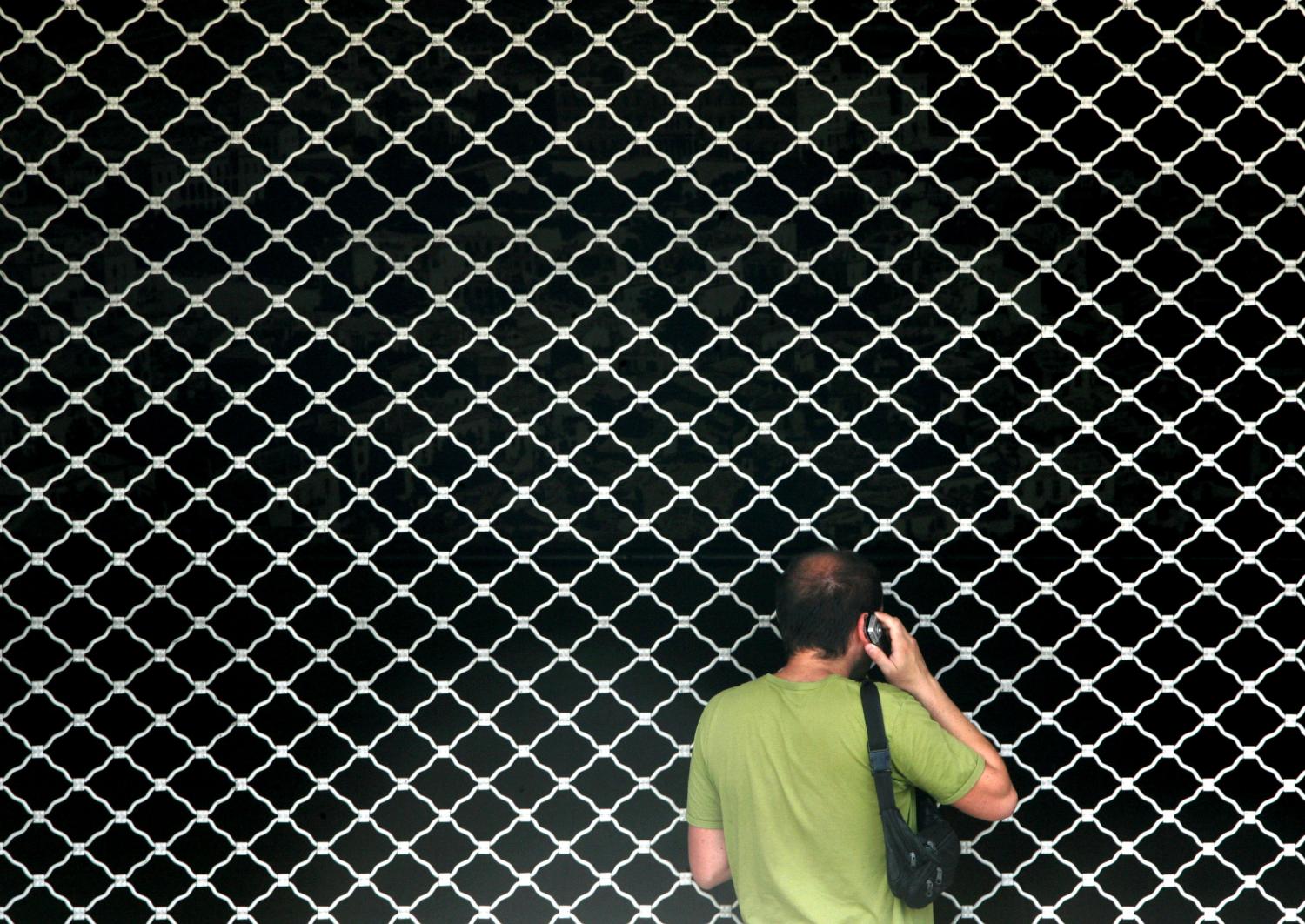 Man speaks on phone as he stands in front of closed metro station in Athens during 24 hour nationwide strike.  A man speaks on the phone as he stands in front of a closed metro station during a 24 hour nationwide strike in Athens July 26, 2005. Greek public and private sector workers held a one-day strike on Tuesday to protest against the government's labour reform plans, causing chaos across the country. REUTERS/Yiorgos Karahalis - RP6DRMSNSUAA