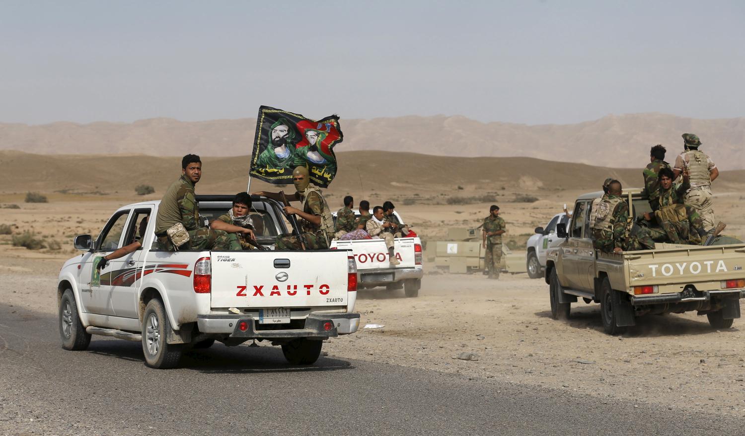 Shi'ite fighters ride on the back of a truck with their weapons in al-Fatha, northeast of Baiji, October 18, 2015. Iraqi forces backed by Shi'ite militia fighters say they have retaken a mountain palace complex of former President Saddam Hussein from Islamic State fighters, as government forces push ahead on a major offensive against the insurgents.   REUTERS/Thaier Al-Sudani  - GF10000249718