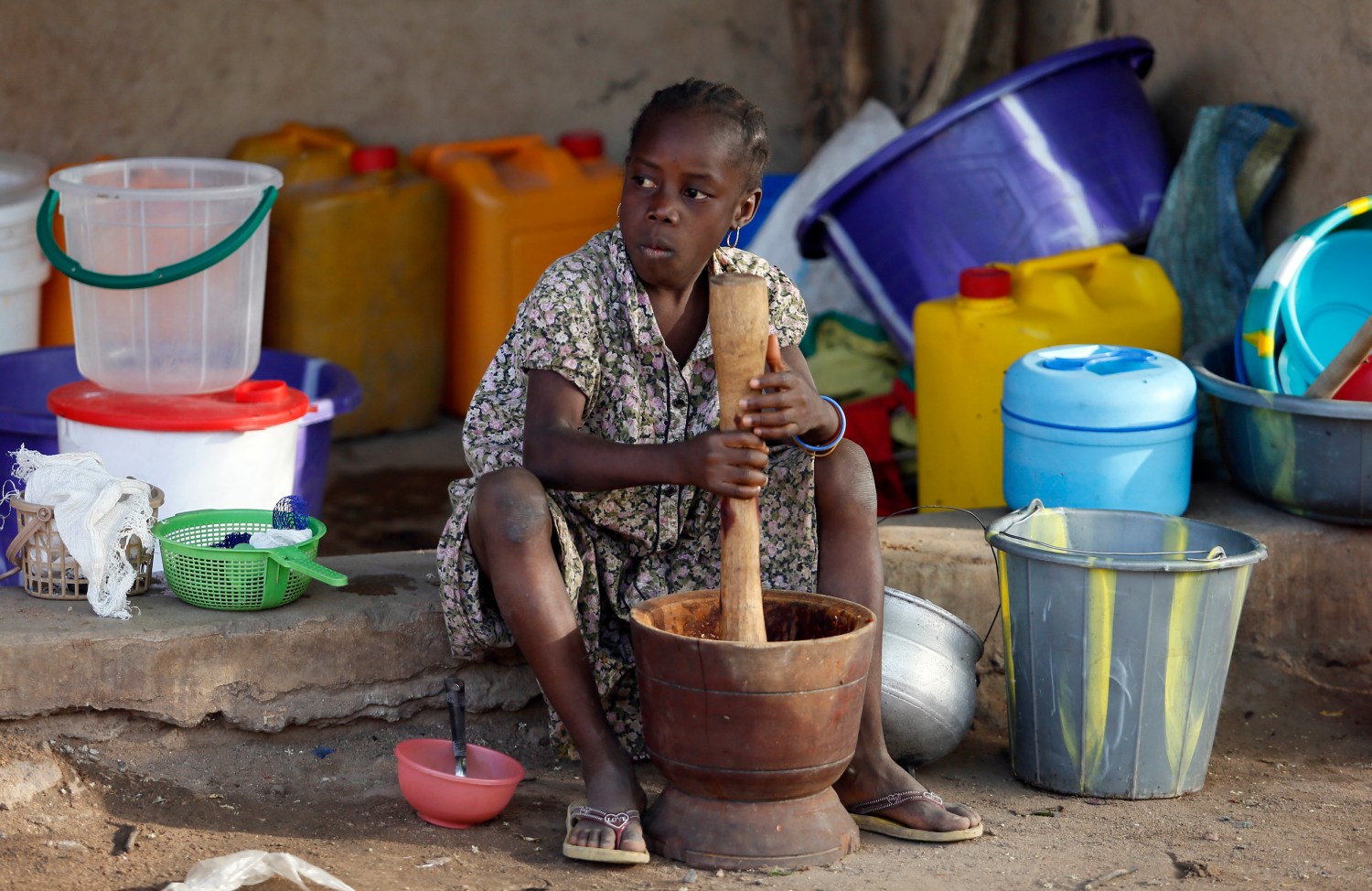 A girl displaced as a result of Boko Haram attacks in the northeast region of Nigeria, uses a mortar and pestle at a camp for internally displaced people in Yola, Adamawa State January 14, 2015. Boko Haram says it is building an Islamic state that will revive the glory days of northern Nigeria's medieval Muslim empires, but for those in its territory life is a litany of killings, kidnappings, hunger and economic collapse. Picture taken January 14. To match Insight NIGERIA-BOKOHARAM/     REUTERS/Afolabi Sotunde (NIGERIA - Tags: CIVIL UNREST SOCIETY EDUCATION) - GM1EB1K12UW01