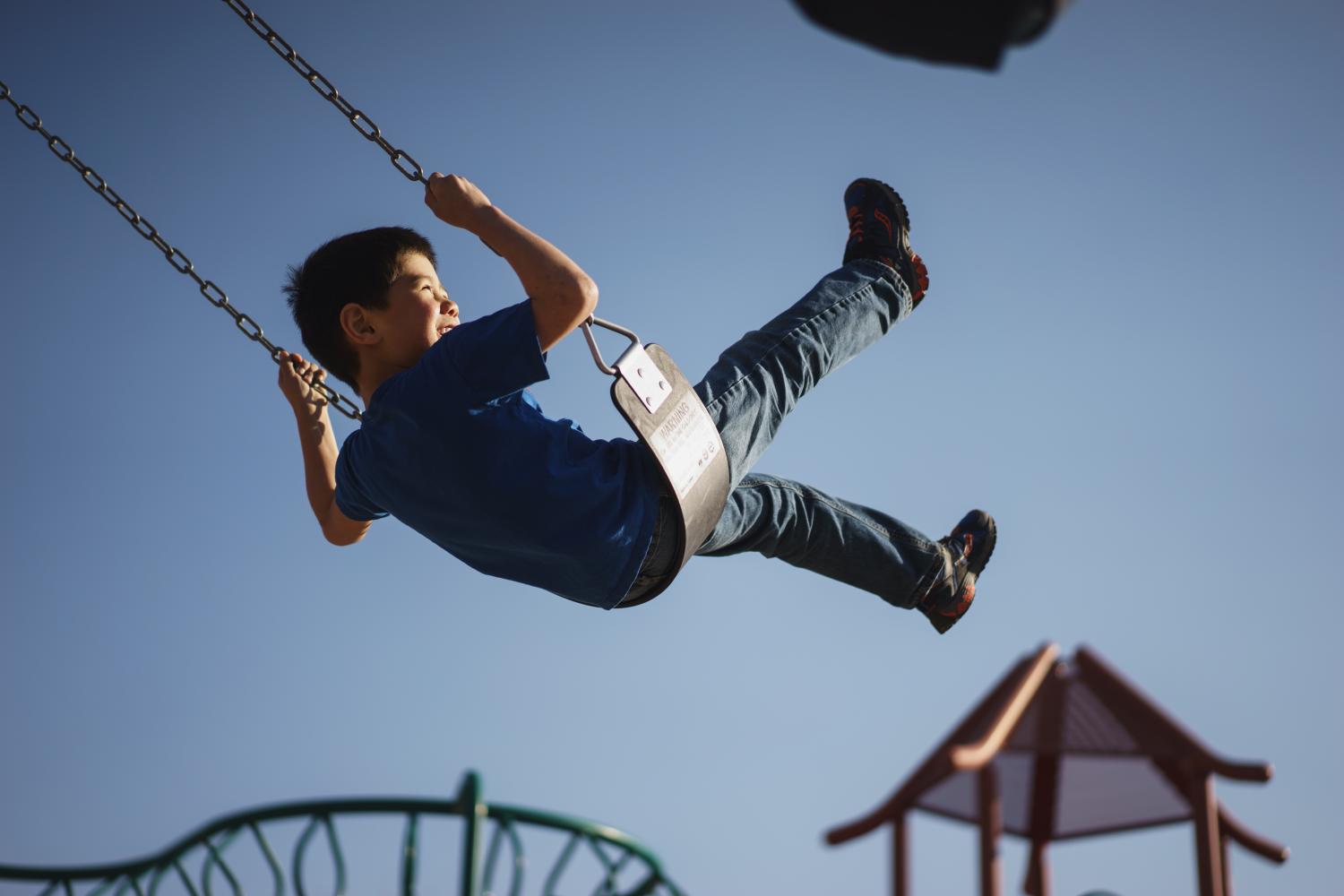 little boy plays on a swingset