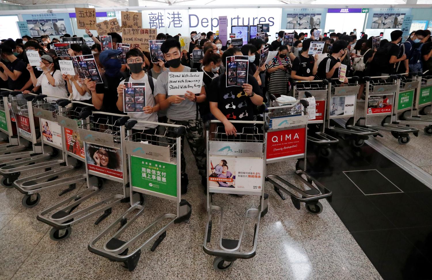 Anti-government protesters stand at a barricade made of trolleys during a demonstration at Hong Kong Airport, China August 13, 2019. REUTERS/Issei Kato - RC1DF4546CB0