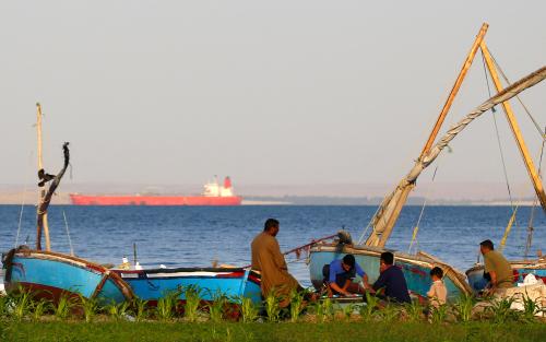 Fishermen take their lunch in front of fishing boats as container ships cross the Red Sea before entering the Suez Canal, in Ismailia port city, northeast of Cairo, Egypt, Egypt October 31, 2018. REUTERS/Amr Abdallah Dalsh - RC1BDB7685C0