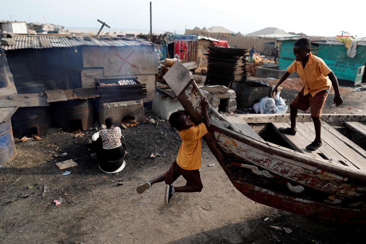 Boys play as a woman prepares smoked fish in Jamestown in Accra, Ghana November 28, 2018. REUTERS/Zohra Bensemra - RC178F9FF100