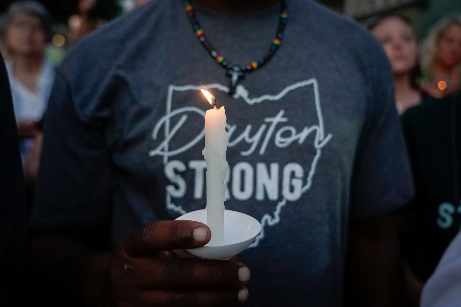 A mourner holds a candle during a vigil at scene of a mass shooting in Dayton