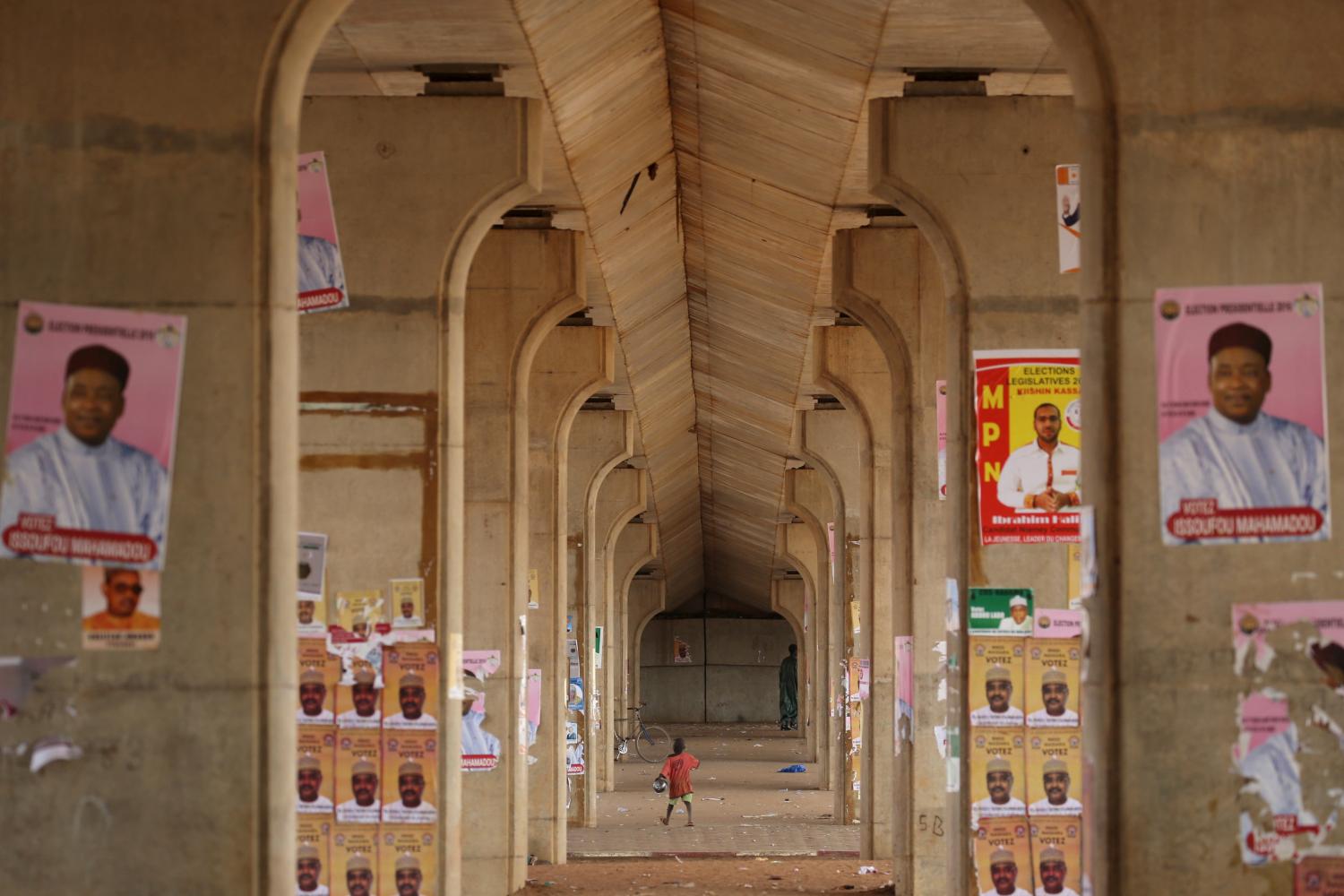 A boy walks past electoral campaign posters for presidential candidates in Niamey, Niger, February 16, 2016. Niger holds presidential and legislative elections on Sunday.  REUTERS/Joe Penney - GF10000311379