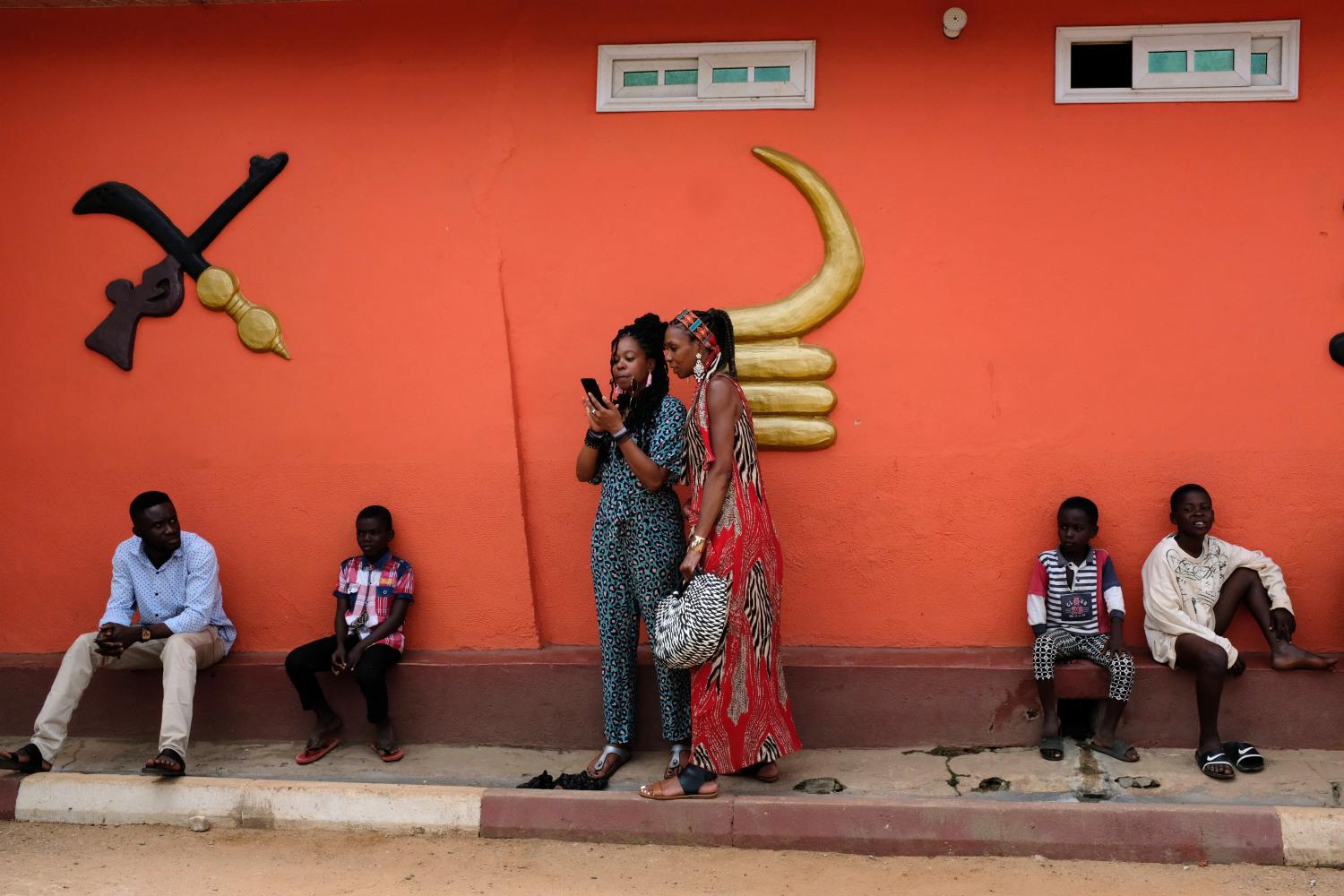 Members of a heritage tour group, who are traveling to Ghana to explore their ancestral roots, look at a mobile phone outside the palace of Nana Boakye Yam Ababio II, Chief of Nkwantakese, in Ashanti region, Ghana August 10, 2019. Picture taken August 10, 2019. REUTERS/Francis Kokoroko - RC1775814300