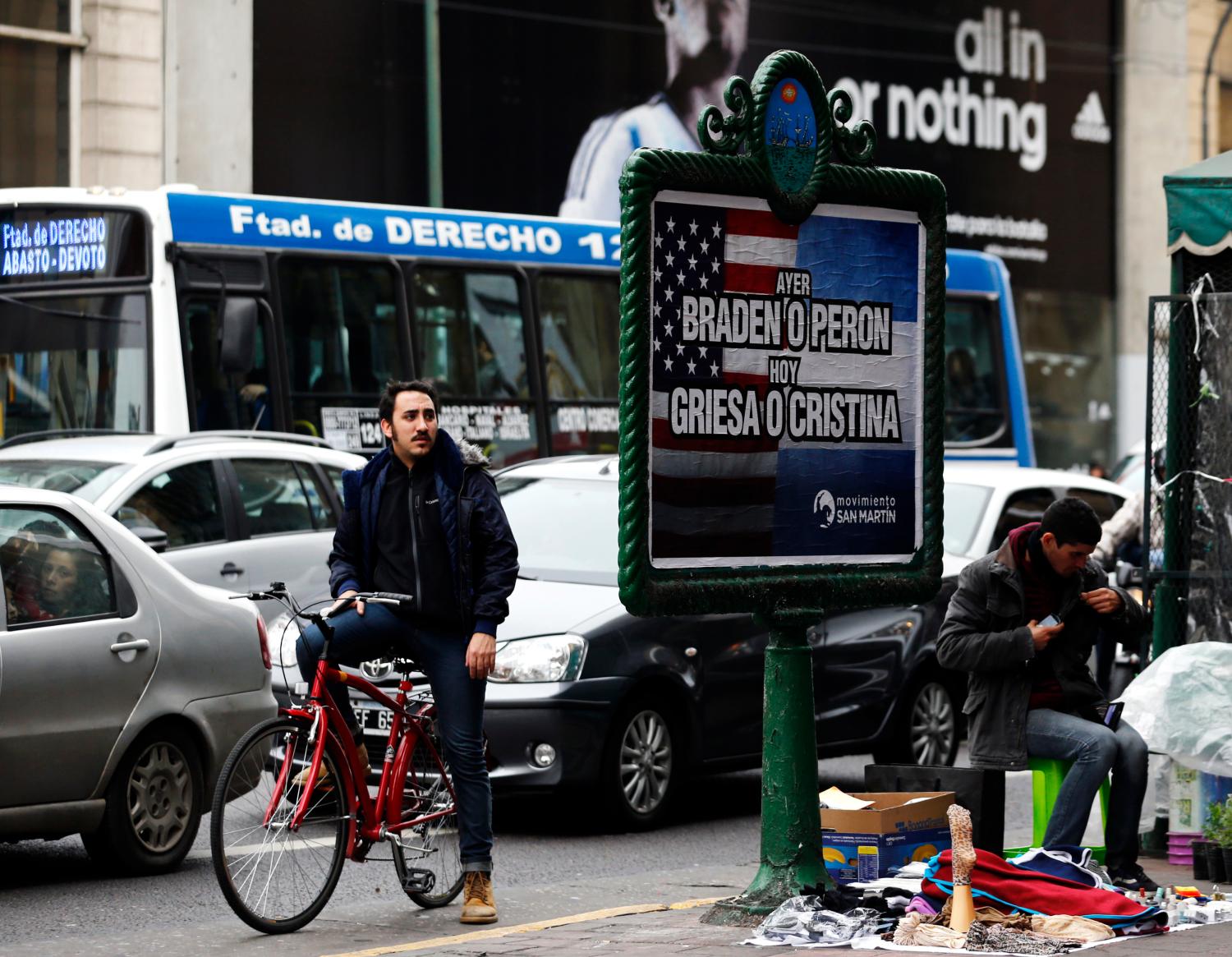 A man looks at a poster placed on an advertising board that reads "Yesterday, Braden or Peron - Today: Griesa or Cristina", in Buenos Aires July 29, 2014. Argentine debt negotiators held talks in New York on Tuesday with the U.S. mediator in the South American country's battle with holdout investors, in a last-ditch attempt to avert a default. After a series of setbacks in U.S. courts, Argentina has until the end of Wednesday to either pay the New York hedge funds in full their defaulted bonds resulting from the country's 2001/02 financial crisis or cut a deal to stave off a fresh default. The poster refers to 1945 U.S. Ambassador in Argentina Braden Spruille, former Argentina's President Juan Peron, U.S. District Court for the Southern District of New York Judge Thomas Griesa and President of Argentina  Cristina Fernandez de Kirchner.   REUTERS/Marcos Brindicci (ARGENTINA - Tags: POLITICS BUSINESS SOCIETY) - GM1EA7U09E501