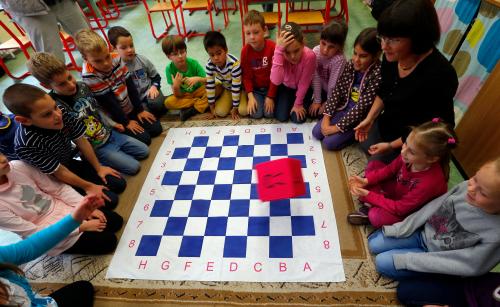 Children use a "chess dice" during a lesson at the Dezso Lemhenyi school, which uses the new "Chess Palace" teaching programme of the world's best female chess player Judit Polgar, in Budapest October 15, 2013. With names like Jumpy Horse, Boom Rook and Tiny Pawn, pieces in the Chess Palace come to life and are like close friends who guide the children through difficult school subjects. They range in size from 1 cm (under half an inch) tall to a meter (three feet) in height. Chairs, walls and carpets also sport chess motifs. The pieces, whose combinations and moves represent mathematical, linguistic or musical patterns, help children develop their skills in chess and in their school studies while making the learning process a more joyous exercise. REUTERS/Laszlo Balogh (HUNGARY - Tags: SPORT CHESS EDUCATION SOCIETY) - GM1E9AO1MXV01