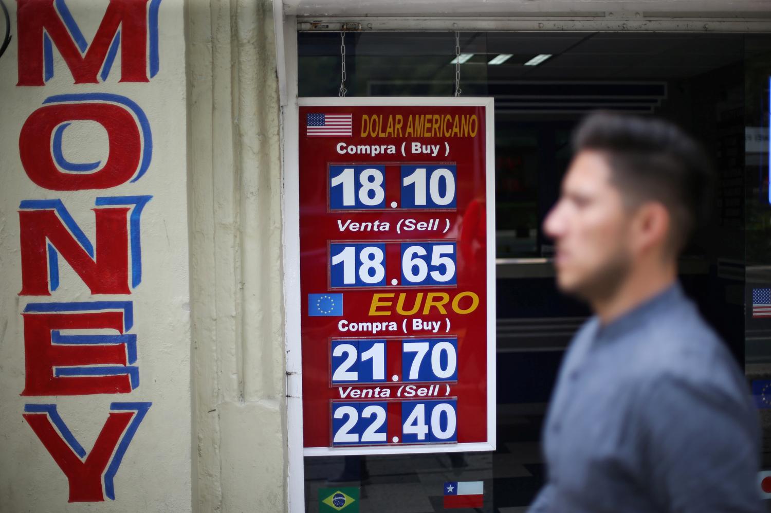 A man walks in front of a board displaying the exchange rate for Mexican Peso and U.S. Dollar at a foreign exchange house in Mexico City, Mexico September 4, 2019. REUTERS/Edgard Garrido - RC1586C1FD60