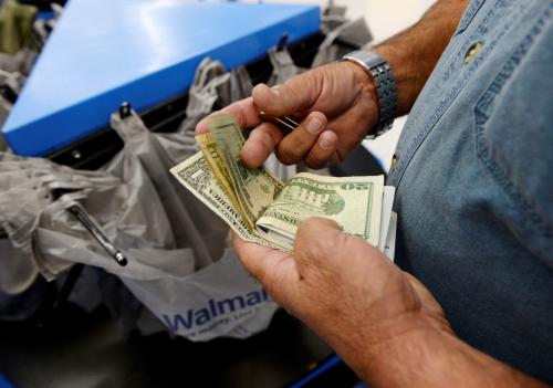 FILE PHOTO: A customer counts his cash at the checkout lane of a Walmart store in the Porter Ranch section of Los Angeles November 26, 2013.   REUTERS/Kevork Djansezian/File Photo          GLOBAL BUSINESS WEEK AHEAD PACKAGE Ð SEARCH BUSINESS WEEK AHEAD MARCH 13 FOR ALL IMAGES - RC1E3B0702B0
