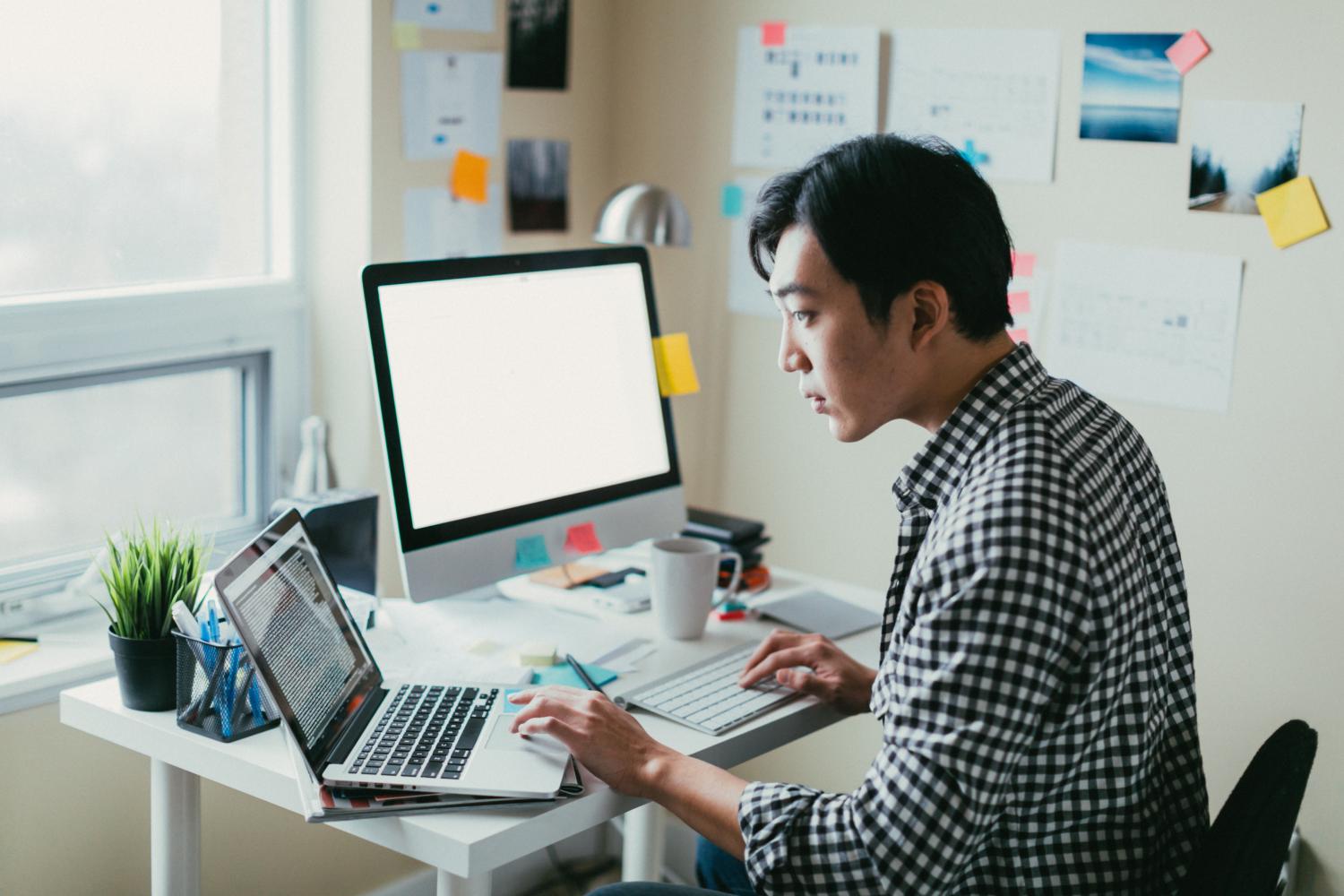 Man looking at laptop while working from his small office.