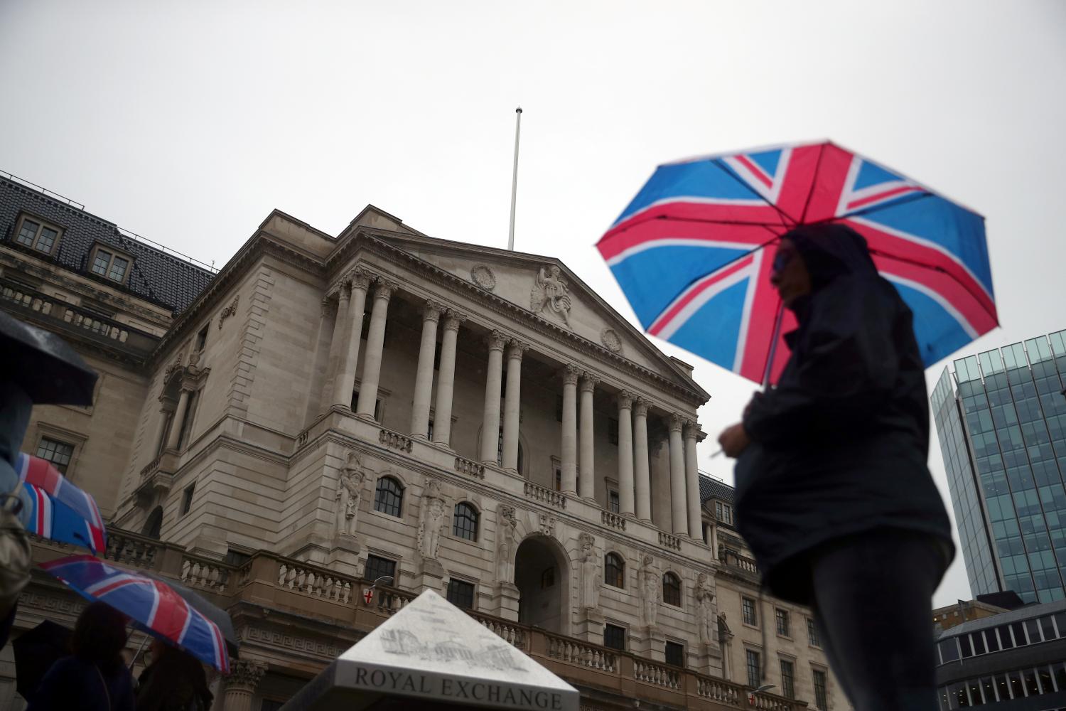 A pedestrian shelters under a Union Flag umbrella in front of the Bank of England, in London, Britain August 16, 2018.  REUTERS/ Hannah McKay - RC1927B08FA0