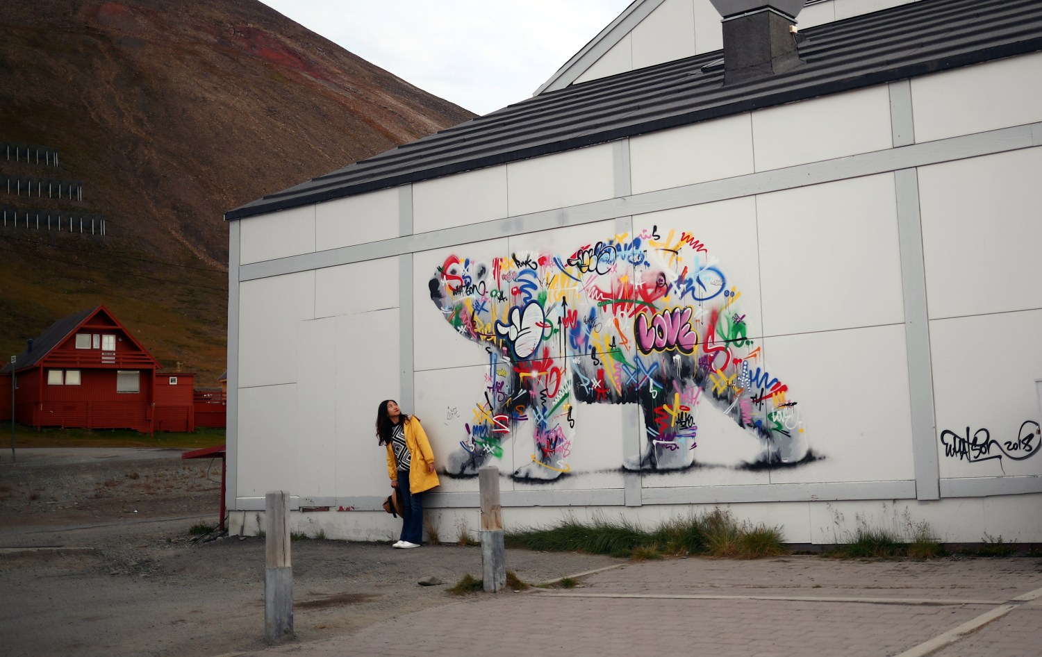 A woman poses next to a polar bear mural in the town of Longyearbyen in Svalbard, Norway, August 6, 2019. REUTERS/Hannah McKay      SEARCH "SVALBARD CLIMATE" FOR THIS STORY. SEARCH "WIDER IMAGE" FOR ALL STORIES. - RC157F319730