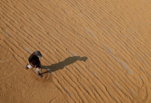 A worker uses his feet to spread rice for drying at a rice mill on the outskirts of Kolkata, India, January 31, 2019.Picture taken January 31, 2019. REUTERS/Rupak De Chowdhuri - RC15F688B6B0