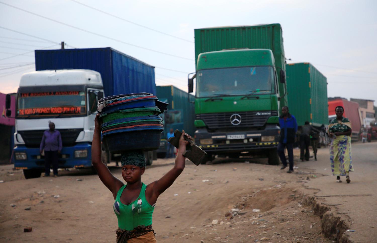 A woman hawks merchandise past transit trucks at Mpondwe border that separates Uganda and the Democratic Republic of Congo, in Mpondwe, Uganda, June 14, 2019. REUTERS/James Akena - RC1ADF153830
