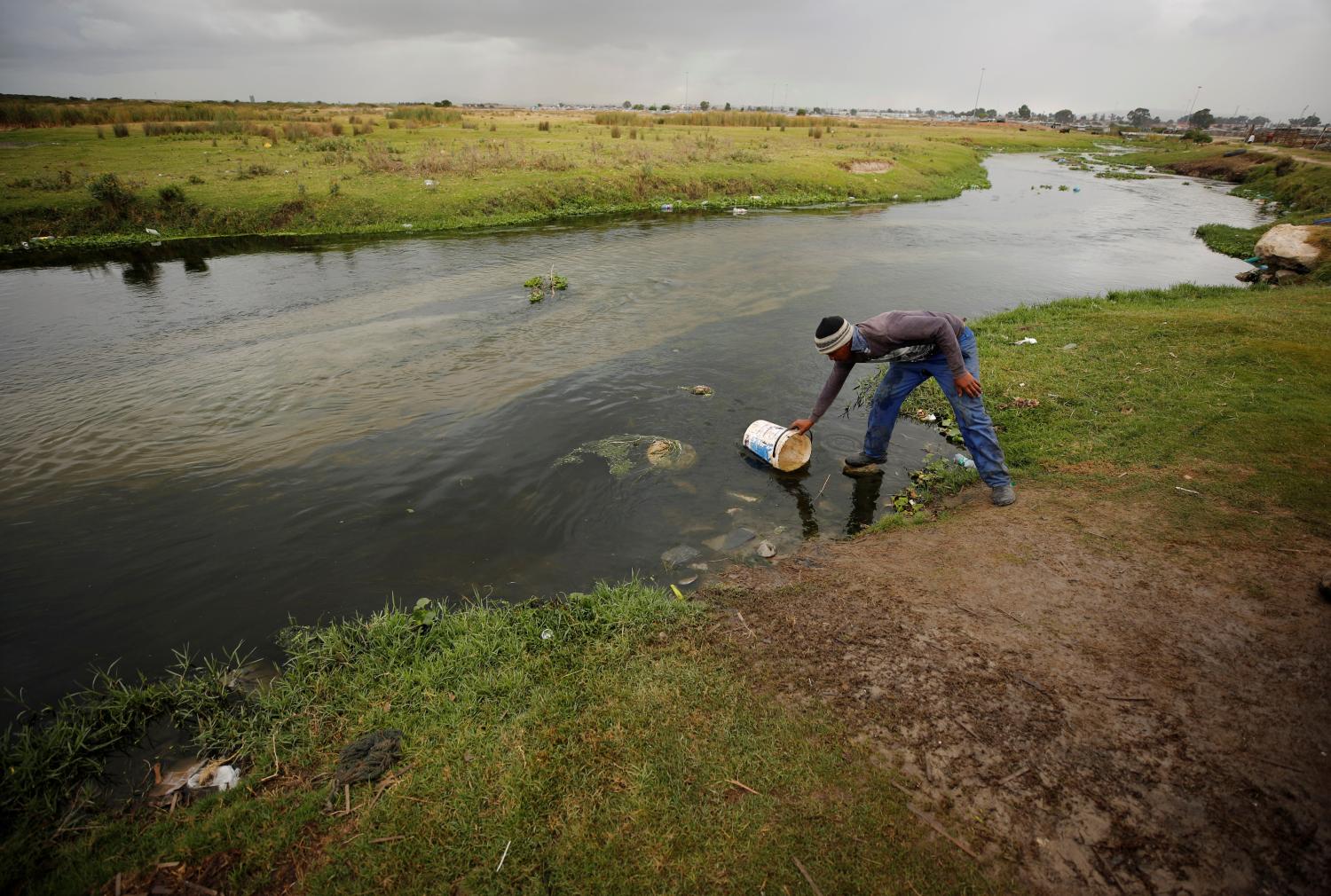 Residents fill containers with water from a polluted river in Cape Town, South Africa, February 2, 2018. REUTERS/Mike Hutchings - RC126C105D10