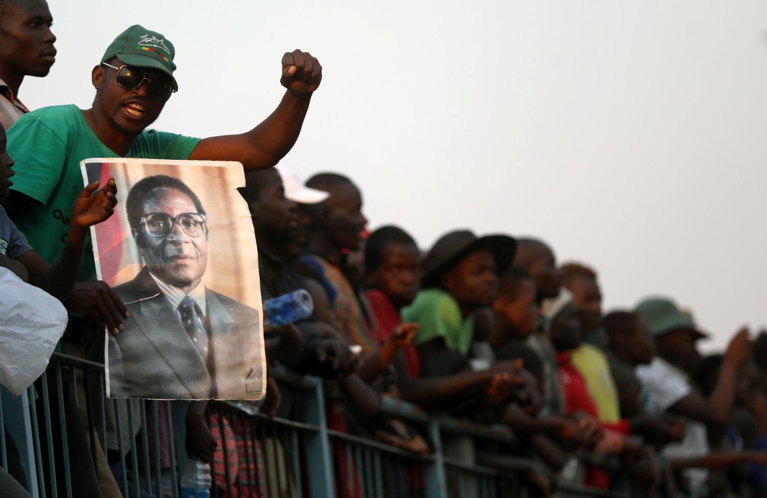 A mourner holds a poster of Robert Mugabe during the viewing of his body
