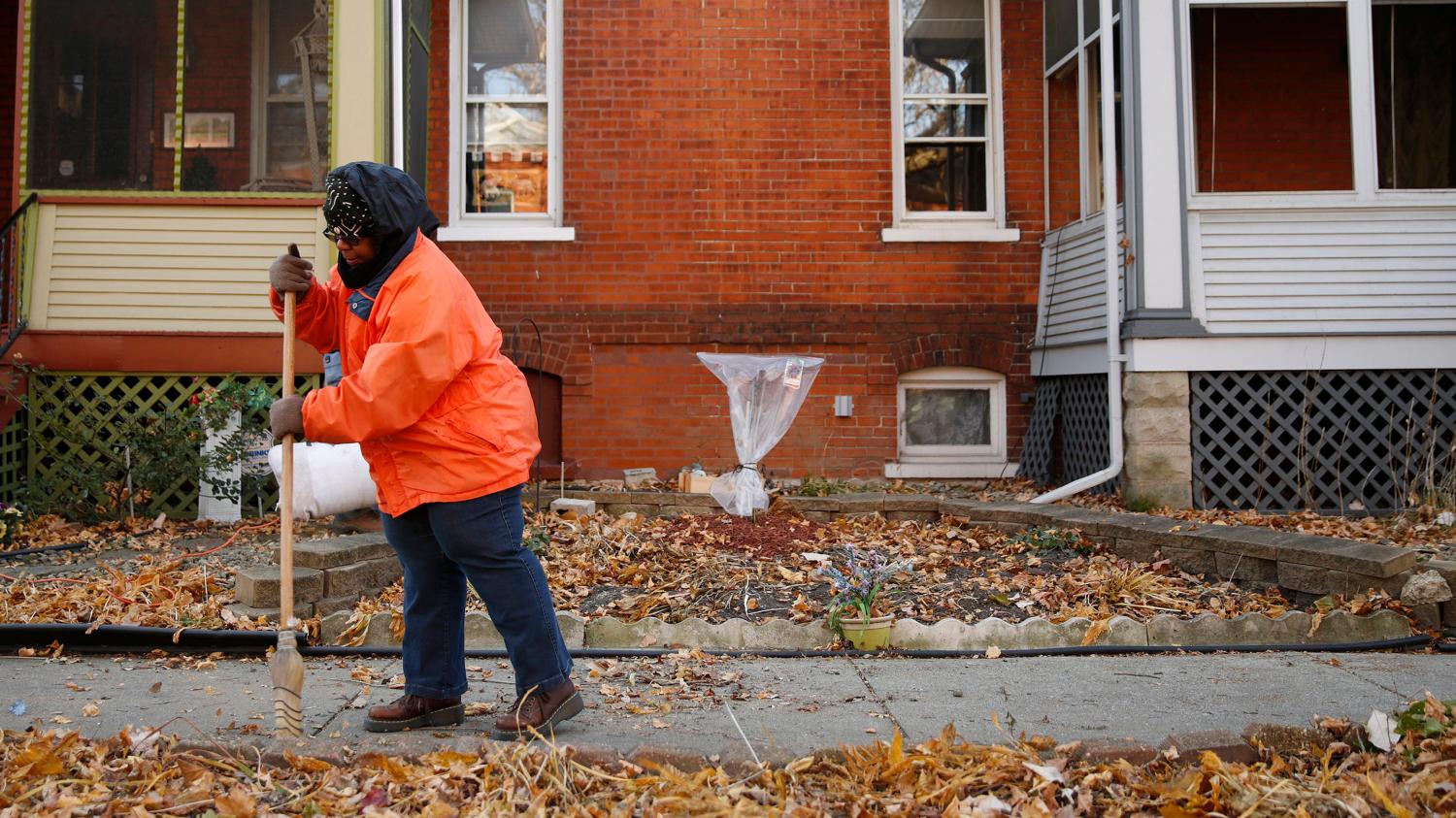 Ardana McFerren sweeps leafs outside of her home in the historic Pullman neighborhood in Chicago November 20, 2014. U.S. President Barack Obama is expected to announce the designation of the Pullman neighborhood as a national park on February 19, according to park advocates. The neighborhood's brick homes and ornate public buildings were built in the 1800s by industrialist George Pullman as a blue-collar utopia to house workers from his sleeper car factory. Picture taken November 20, 2014.  REUTERS/Andrew Nelles (UNITED STATES - Tags: SOCIETY ENVIRONMENT POLITICS) - TM3EABN1EN701