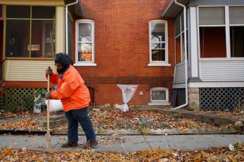 Ardana McFerren sweeps leafs outside of her home in the historic Pullman neighborhood in Chicago November 20, 2014. U.S. President Barack Obama is expected to announce the designation of the Pullman neighborhood as a national park on February 19, according to park advocates. The neighborhood's brick homes and ornate public buildings were built in the 1800s by industrialist George Pullman as a blue-collar utopia to house workers from his sleeper car factory. Picture taken November 20, 2014.  REUTERS/Andrew Nelles (UNITED STATES - Tags: SOCIETY ENVIRONMENT POLITICS) - TM3EABN1EN701