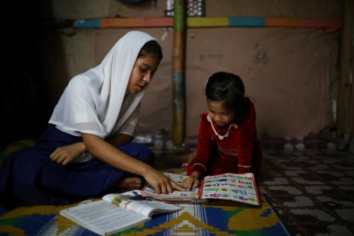 Yasmin, a Rohingya girl who was expelled from Leda High School for being a Rohingya, helps her younger sister to study in Leda camp in Teknaf, Bangladesh, March 5, 2019. REUTERS/Mohammad Ponir Hossain - RC14D96237D0