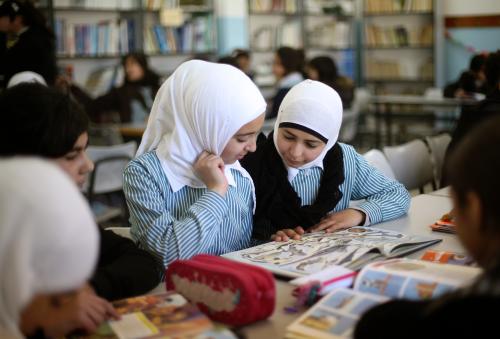 Palestinian students share a schoolbook while studying in the school library in the West Bank city of Ramallah February 4, 2013. Israelis and Palestinians depict each other in schoolbooks as an enemy and largely deny their adversary's history and existence, according to a U.S. government-funded study published on Monday. REUTERS/Mohamad Torokman (WEST BANK - Tags: POLITICS EDUCATION) - GM1E9241TXY01