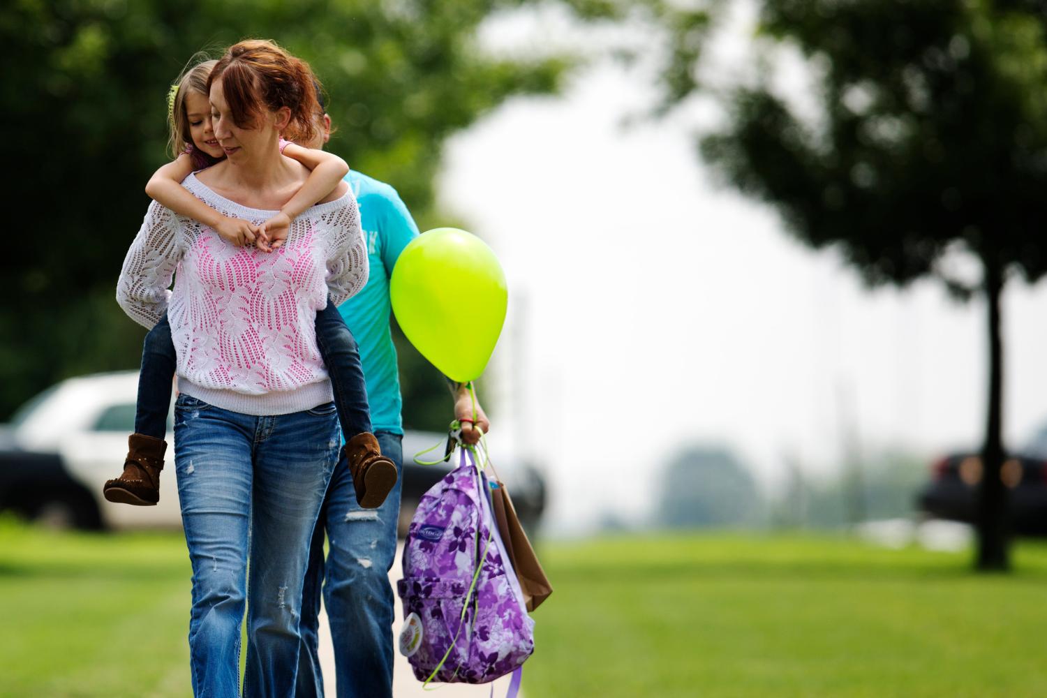 Jayme Sheppard carries her daughter Hope, who was enrolled in kindergarten at the Plaza Towers elementary school, on her shoulders as she departs a ceremonial last day of the school year at the Eastlake Elementary School in Oklahoma City, Oklahoma, May 23, 2013. Seven students were killed at Plaza Towers Elementary when a tornado packing winds of 200 miles (320 km) per hour slammed into the building on Monday afternoon just before school was to have let out. The massive tornado obliterated sections of Moore, Oklahoma, leaving 24 dead on May 20. REUTERS/Lucas Jackson (UNITED STATES - Tags: DISASTER ENVIRONMENT) - GM1E95O08WU01