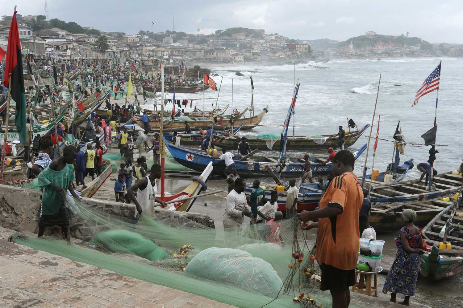 Fishermen tend their boats and fishing nets as members of a heritage tour group, traveling to Ghana to discover their roots, visit the Cape Coast castle, Ghana August 12, 2019. Picture taken August 12, 2019. REUTERS/Kweku Obeng - RC16CBB8F0D0
