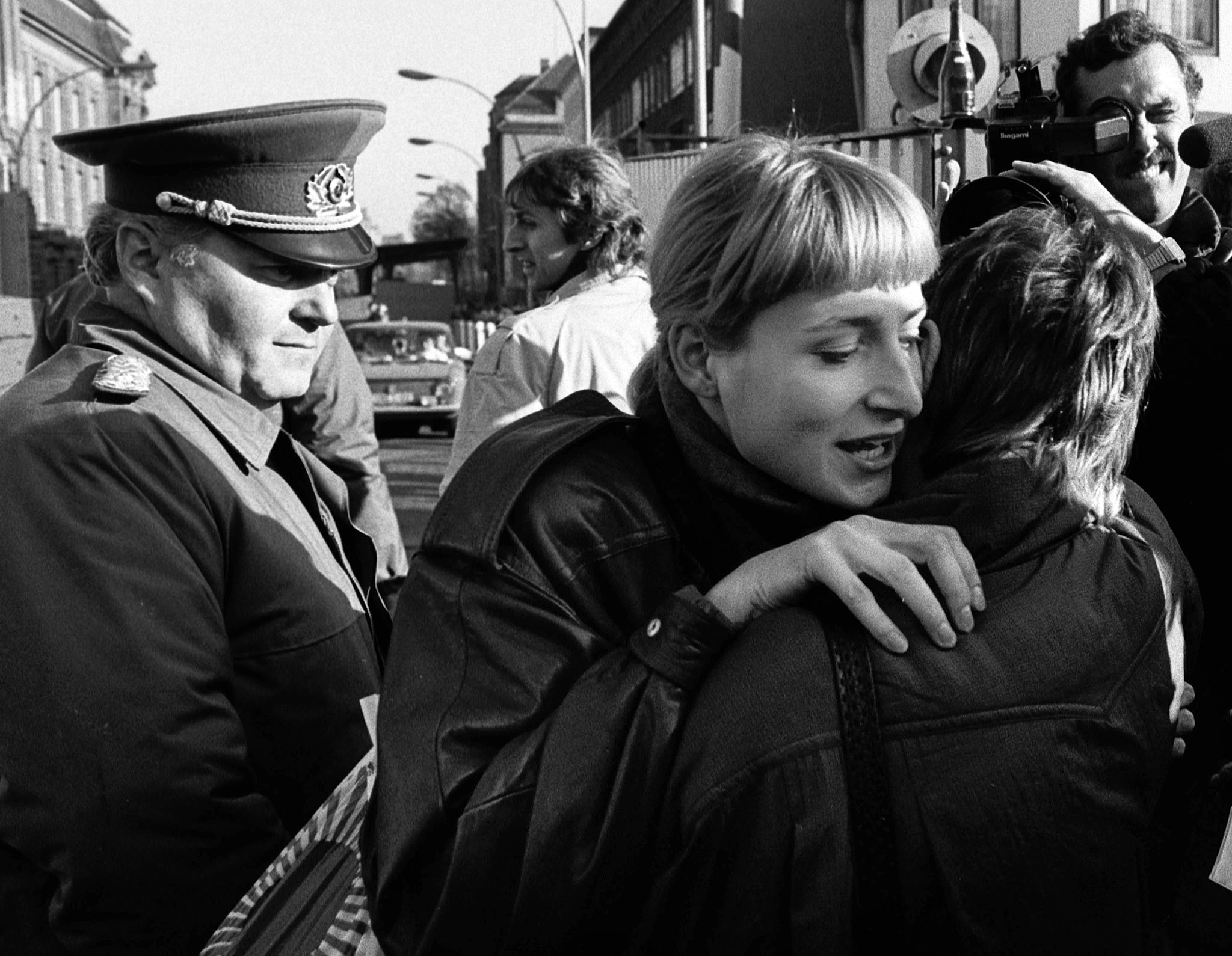 An East Berliner and a West Berliner embrace while a border soldier looks on, November 10, 1989. (Reuters)