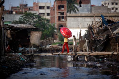 A man carries an umbrella as he crosses a bamboo made bridge near a tannery at Hazaribagh along the polluted Buriganga river in Dhaka June 5, 2014. Bangladesh's Prime Minister Sheikh Hasina warned the tannery owners at Hazaribag of serious consequence if they failed to relocate their tanneries in Savar within the stipulated time, during a World Environment Day observance program, local media reported. According to the United Nations Environment Programme website, World Environment Day is celebrated annually on June 5 to raise global awareness and motivate action for environmental protection. REUTERS/Andrew Biraj (BANGLADESH - Tags: ENVIRONMENT) - GM1EA651RI801