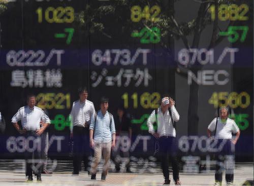 Passersby are reflected on a stock quotation board outside a brokerage in Tokyo, Japan, August 6, 2019.   REUTERS/Issei Kato - RC1DCEB91510