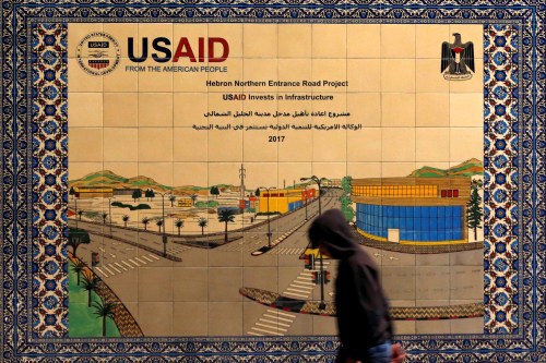 A Palestinian walks past a ceramic sign of a U.S. Agency for International Development (USAID) project in Hebron in the Israeli-occupied West Bank January 31, 2019. Picture taken January 31, 2019. REUTERS/Mussa Qawasma - RC1DBE2B9C60