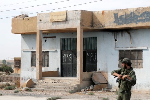 Turkey-backed Syrian rebel fighter stands near a former YPG office at the entrance of Tel Abyad, Syria, October 14, 2019. REUTERS/Khalil Ashawi - RC1A61702270